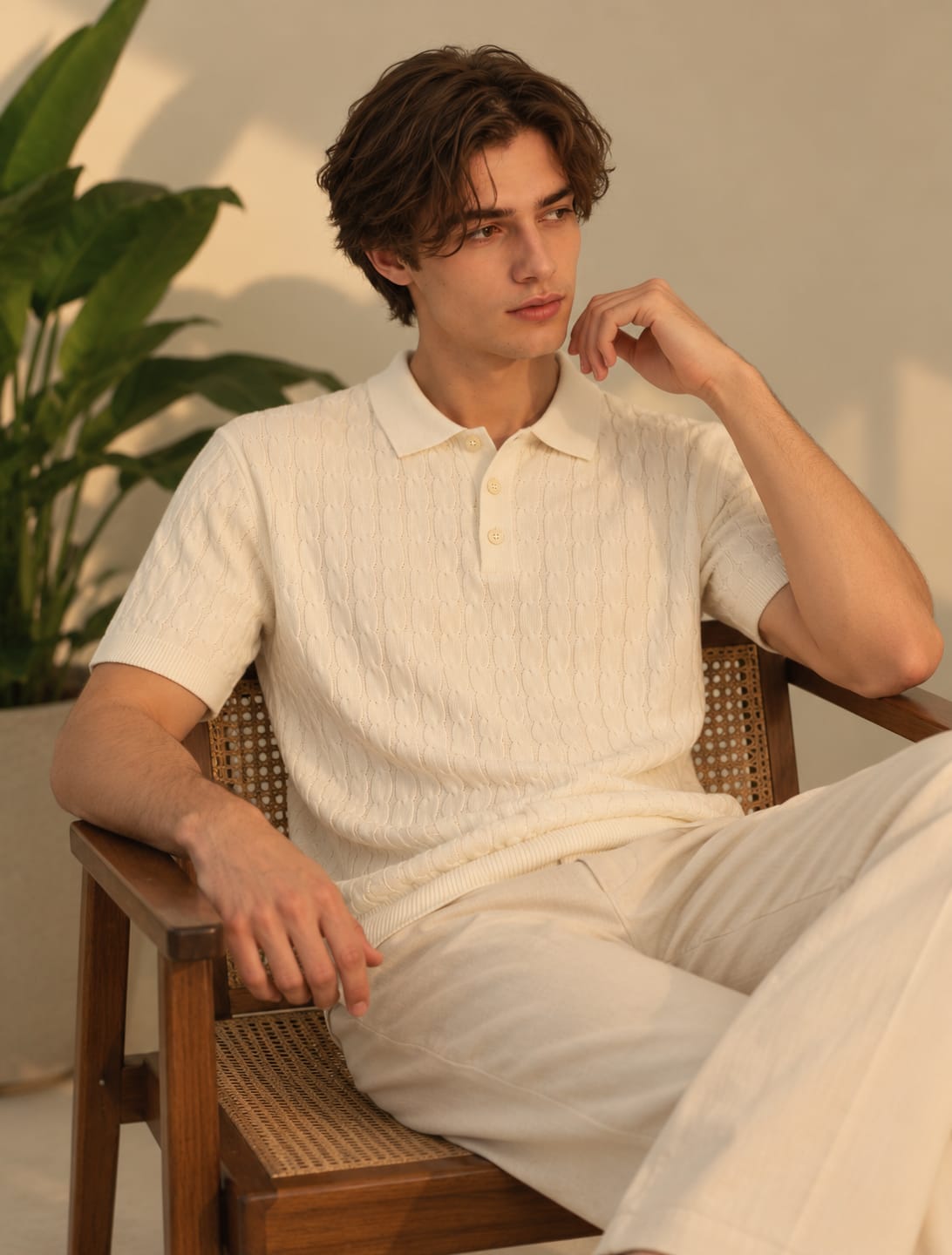 Model wearing BEZOKE cream cable knit short-sleeve polo with cream trousers
